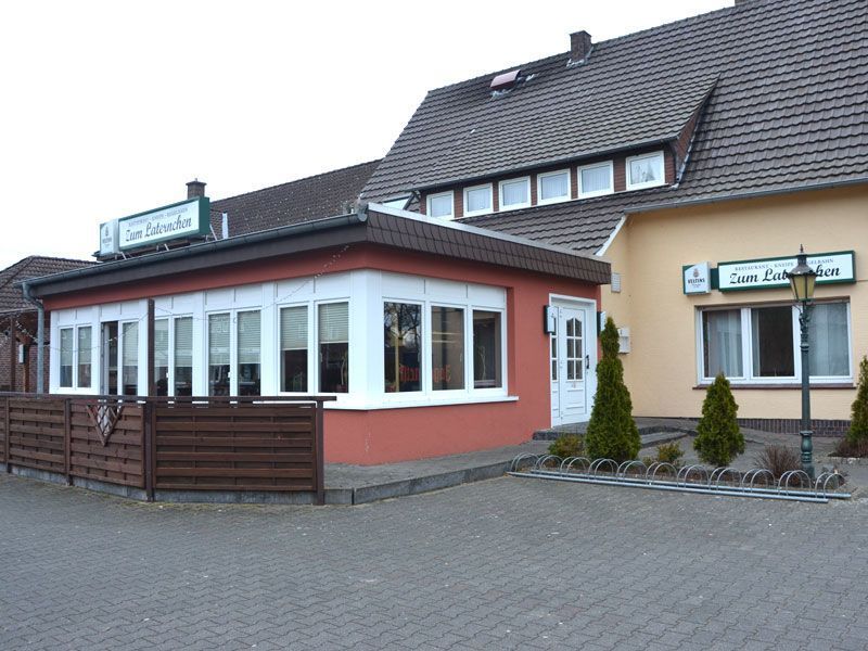 Gebäude des Restaurants Zum Laternchen, rote Fassade, weiße Fenster, ruhige Umgebung, Laterne vorne.